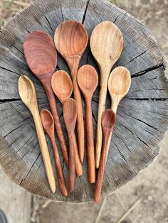 five wooden spoons sitting on top of a piece of wood next to each other