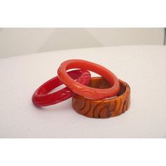 This is part of Chairish’s Costume Jewelry assortment.  The set of 3 art deco vintage authentic carved bangle bakelite bracelets are in the hues of red, amber orange and caramel. They are all hand carved and the orange caramel one is a thicker cuff with small swirls of black. The caramel on is 1.25" H x 3" W and the interior of that one is approx. 2.5" W. The other two are .5" H x 3.5" W and the other of those are 2.5" W. They will fit over a small medium wrist or medium wrist but not an extra w Red Carved Vintage Jewelry, Carved Red Vintage Jewelry, Vintage Red Round Bangle, Vintage Handmade Red Bangle, Red Retro Bangle Jewelry, Vintage Carved Orange Jewelry, Vintage Orange Carved Jewelry, Orange Carved Vintage Jewelry, Handmade Bakelite Bangle Bracelet