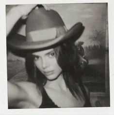 a black and white photo of a woman wearing a cowboy hat