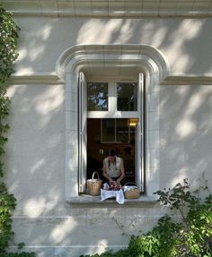 a person sitting in a window sill with baskets