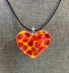 "There are no two pendants alike that is for sure with these handmade glass pendants. These pendants are made with murrini and chips of glass called frit. I call this pendant field of poppies because of the murrini. The method to create the piece gives it depth and an abstract look. No two are the same!  This heart shaped pendant measures approximately 1.5\" length and 1.25\" in width. The pendant  comes with an 18\" black cord that gives it a casual look but it is very versatile and can work with gold or silver as well.  Made in the USA Each piece is carefully made in my home studio. In addition to multiple firings in a kiln there is time spent with each piece carefully designing the piece, selecting the glass, cutting, shaping, grinding and cleaning it so it is just right!  I hope you en Field Of Poppies, Movie Ideas, Heart Shaped Pendant, Sunflower Yellow, Heart Shaped Necklace, Heart Shape Pendant, Glass Heart, Red Poppies, Glass Pendants