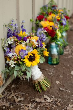 three vases filled with flowers sitting next to each other on the side of a building