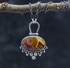 This pendant features a Agua Nueva agate. It's a phenomenal stone, which is rather hard to find in this quality lately. the color and pattern are top notch and so beautiful. It has a hinged bail and sweet ruffle of silver ball details. Flip the pendant over and I have textured the metal with a pattern that mimics the pattern in the stone. The piece is just over 1 inches wide and 1 3/4 inches long ♦Chain: This comes on a oval link chain that is currently 18-20 inches. It has a lobster claw clasp Luxury Agate Round Pendant Necklace, Luxury Cabochon Pendant Gemstones, Luxury Metal Cabochon Jewelry, Luxury Artisan Oval Pendant Jewelry, Raw Jewelry, Sterling Silver Gemstone Necklace, 2024 Jewelry, Silver Necklace Designs, Silversmithing Jewelry