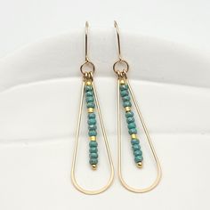 Adorn yourself with opulence and grace with the captivating Harley earrings. Made from gleaming gold, these long teardrop earrings are adorned with delicate turquoise seed beads, adding a touch of exotic charm to your look. Elevate any outfit with these luxurious and alluring earrings. Approximately 2.25” long Made with 14k Gold Filled Turquoise Seed Beads Polished to a high shine Handmade in Montana Sent in a ribboned gift box with polishing cloth Elegant Turquoise Beaded Earrings With Gold Beads, Long Drop Teardrop Earrings With Dangling Beads, Turquoise Teardrop Pearl Drop Earrings, Gold Beaded Dangle Teardrop Earrings, Elegant Turquoise Earrings With Gold Beads, Elegant Teardrop Beaded Brass Earrings, Elegant Brass Teardrop Beaded Earrings, Metal Teardrop Earrings With Dangling Beads, Fall Forward