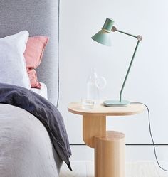 a table with a lamp on it next to a bed