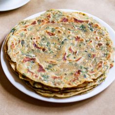 three flatbreads on a white plate next to a cup and saucer