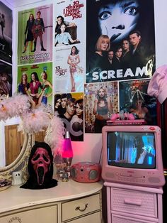 a room filled with lots of pink and white items on top of a dresser next to a wall covered in movie posters