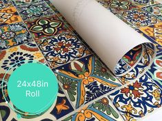 a roll of white paper sitting on top of a colorful tile floor with the words 24x34in roll