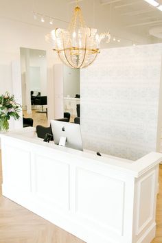 a white reception desk with a chandelier hanging from the ceiling