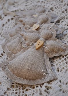 three pieces of cloth with wooden buttons on them sitting on a lace doily covered tablecloth