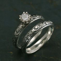 two wedding rings with an engraved design on each side and a diamond in the middle