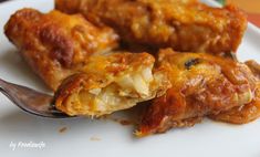 a white plate topped with meat and cheese covered enchiladas next to a fork