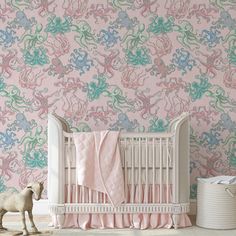 a baby crib in front of a pink wallpaper with blue and green swirls