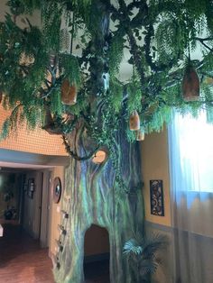 a large tree with lots of green leaves on it's trunk and branches hanging from the ceiling