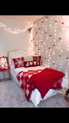 a bedroom decorated in red and white with christmas lights on the wall behind the bed