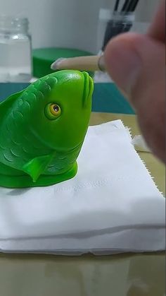 a green toy fish sitting on top of a white napkin