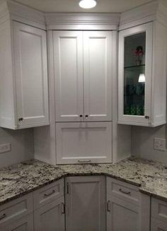 a kitchen with white cabinets and granite counter tops in the corner, along with two lights