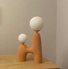 an orange and white sculpture sitting on top of a wooden table next to a wall