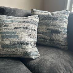 two pillows sitting on top of a gray couch