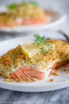 a piece of salmon on a white plate with lemon wedges and dill sprigs