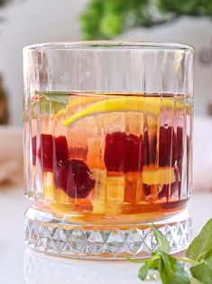 a glass filled with fruit and juice on top of a table