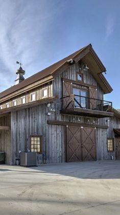 a large wooden building sitting on top of a cement lot next to a tall tree