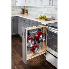 an open cabinet with pots and pans in the middle of a kitchen countertop