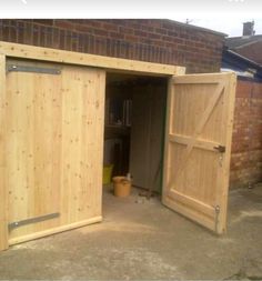 an open wooden garage door on the side of a brick building