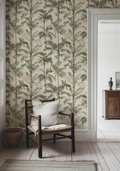 a chair sitting in front of a wallpaper with palm trees on it and a potted plant