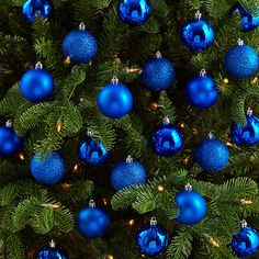 blue ornaments are hanging from the branches of a christmas tree