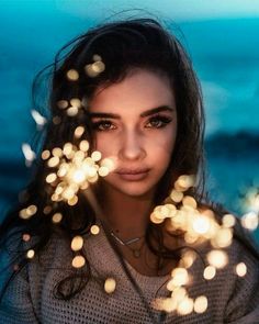 a woman standing in front of the ocean with her eyes closed and lights coming out