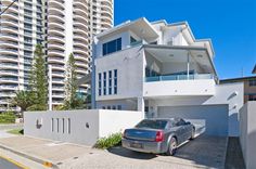 a car parked in front of a tall white building with balconies on the sides