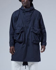 The Indigo C/N Anorak is a lightweight overcoat. The fabric is a cotton and nylon blend. The Indigo C/N Anorak features a hood with a drawcord, half-zip closure, a D ring, two bust pockets, and a fishtail hem. The Indigo C/N Anorak is designed with a looser fit, with the hem hitting just above the knee. We recommend taking your normal size for an oversized fit. The model stands 6' and wears size M. Snow Peak, Long Parka, Customer Stories, Brace Yourself, Bellows, History Design, D Ring, Above The Knee, Half Zip