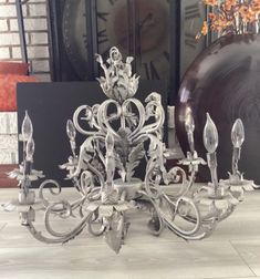 a silver chandelier sitting on top of a white tile floor next to a clock