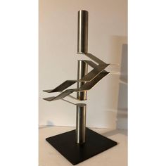 a tall metal sculpture on top of a black square base with three intersecting sections in the middle