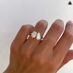 a woman's hand with a diamond ring on her left hand and the other hand holding an engagement ring