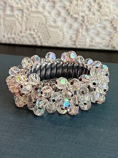 This is a fun, shimmery cha-cha style of vintage bracelet loaded with sparkly iridescent Aurora Borealis crystals. This 6 - 7 inch, silvertone bracelet with expandable watchband underneath is an easy way to add shimmer to any outfit. With such high quality it makes a great vintage gift for lovers of Aurora borealis crystals. This bracelet can be worn casually or dressed up for special occasions, adding a touch of elegance and interest to any look. The changing colors make them a versatile access Vintage Beaded Bracelets For Party, Vintage Crystal Bracelet For Party, Vintage Adjustable Crystal Bracelet For Party, Vintage Beaded Adjustable Crystal Bracelet, Vintage Adjustable Beaded Crystal Bracelet, Adjustable Beaded Vintage Crystal Bracelet, Vintage Crystal Bracelets For Party, Vintage Adjustable Stretch Bracelet For Party, Adjustable Vintage Stretch Bracelet For Party