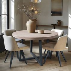 a dining room table with four chairs and a vase on the table next to it