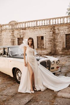 a woman in a white dress standing next to a car