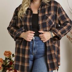 a woman standing in front of a wall wearing a black and brown checkered shirt