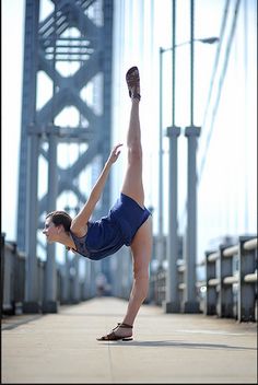 a woman doing a handstand in front of a bridge