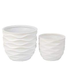 two white vases sitting next to each other on a white surface with wavy designs