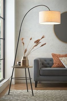 a living room with a gray couch and round mirror on the wall next to it