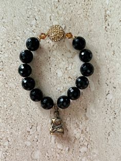 Buddha Bracelet features stunning 12MM faceted black onyx stones accented with a topaz pave 14MM focal bead, 6MM topaz a/b Swarovski crystals and a brass sitting Buddha charm.  Bracelet measures approximately 7 inches and is strung on stretch cord.  Handmade. GIFT BOXED Elegant Gemstone Beads Stretch Bracelet For Meditation, Faceted Black Crystal Bracelet Gift, Elegant Crystal Gemstone Bracelet For Meditation, Elegant Beaded Crystal Bracelet For Meditation, Elegant Beaded Agate Crystal Bracelet, Adjustable Black Beaded Bracelets With Stones, Black Gemstone Beads Bracelets For Jewelry Making, Spiritual Beaded Obsidian Bracelets, Spiritual Black Beaded Bracelets With Stones