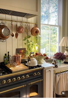 a kitchen with pots and pans hanging on the wall next to an open window