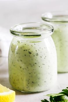 three jars filled with green sauce next to lemon wedges