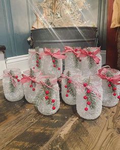 several glass jars with red and white bows are sitting on the floor next to a christmas tree