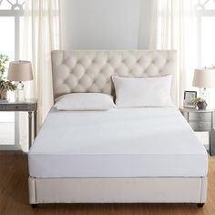 a bed with white sheets and pillows in a room