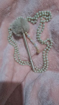 a necklace with pearls and a tassel on top of it, laying on a pink blanket