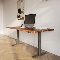 a computer monitor sitting on top of a wooden desk next to a white wall in an empty room